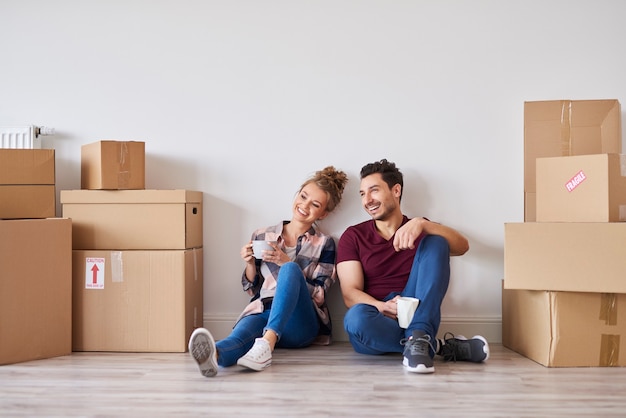 Couple heureux avec des tasses à café se détendre dans leur nouvelle maison