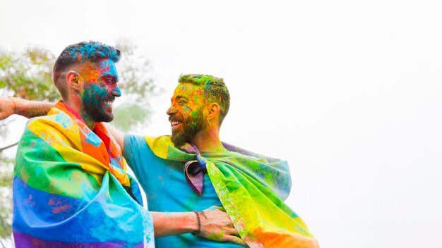 Couple homosexuel avec des visages peints rire et embrasser