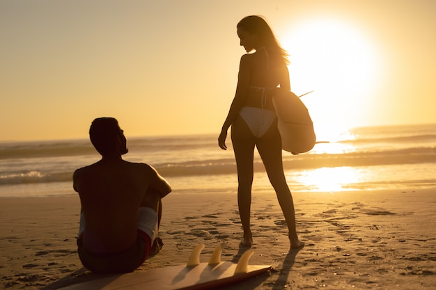 Couple interagissant les uns avec les autres sur la plage pendant le coucher du soleil