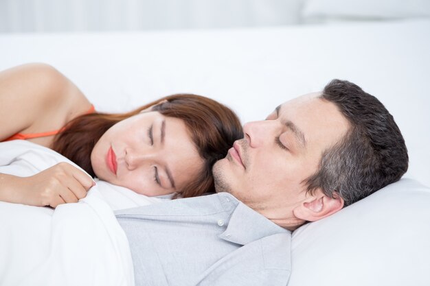 Couple interracial affectueux dormant dans le lit