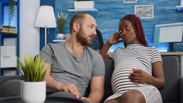 Photo gratuite couple interracial attend un enfant et se lie sur un canapé