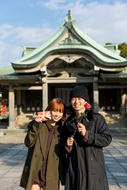 Photo gratuite couple japonais posant avec des cadeaux lors d'un rendez-vous à l'extérieur