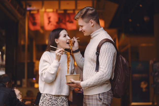 Couple de jeunes mariés manger des nouilles avec des baguettes à Shanghai à l'extérieur d'un marché alimentaire