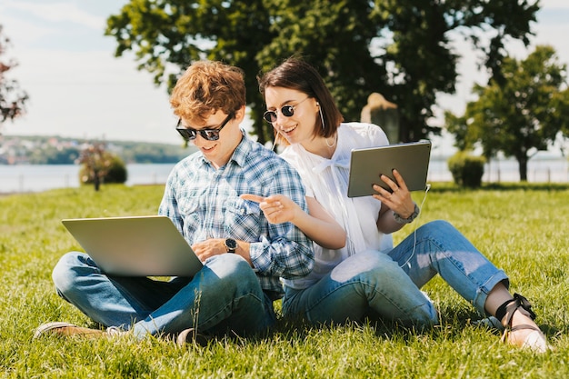 Couple de jeunes pigistes travaillant dans le parc