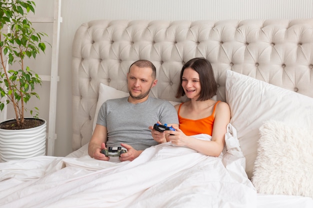 Couple jouant à des jeux vidéo au lit