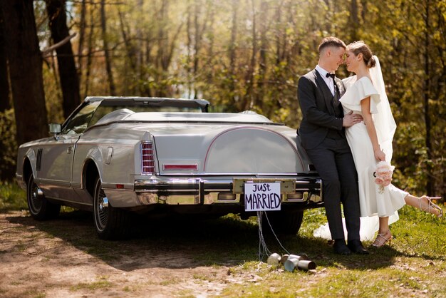 Couple juste marié avec leur voiture