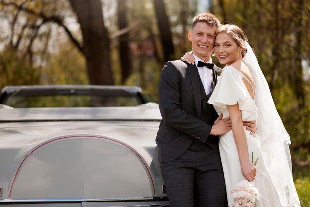 Couple juste marié avec leur voiture