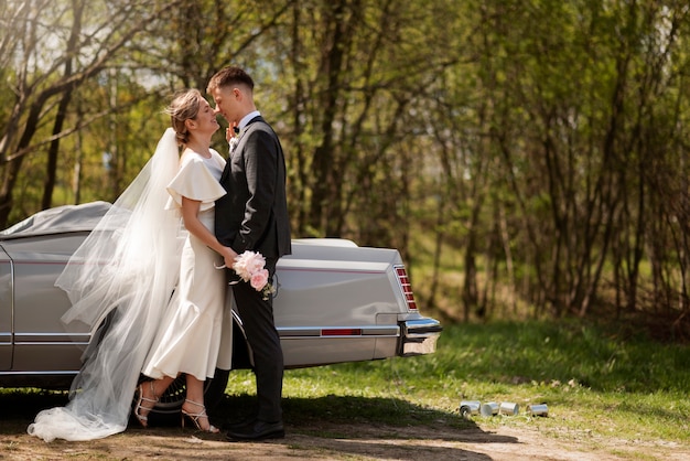 Photo gratuite couple juste marié avec leur voiture