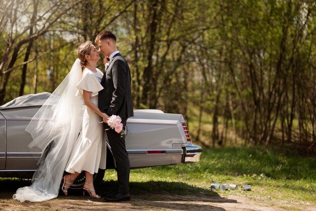 Couple juste marié avec leur voiture