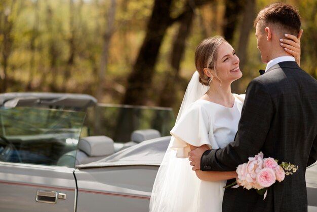 Couple juste marié avec leur voiture