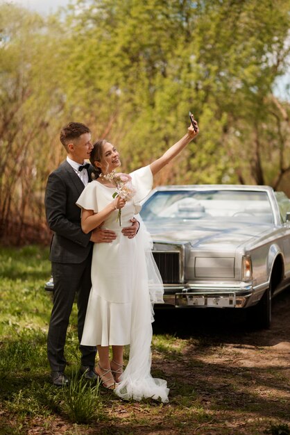 Couple juste marié avec leur voiture