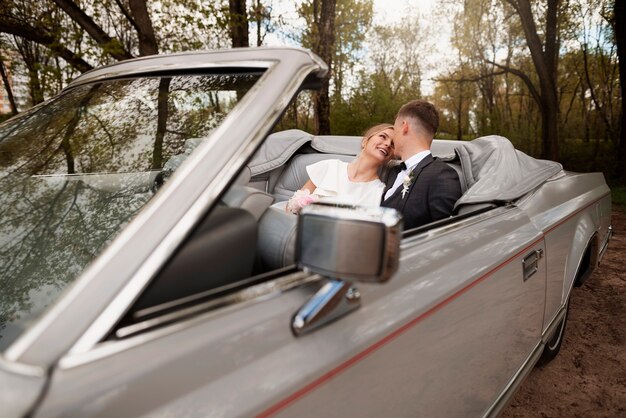 Couple juste marié avec leur voiture