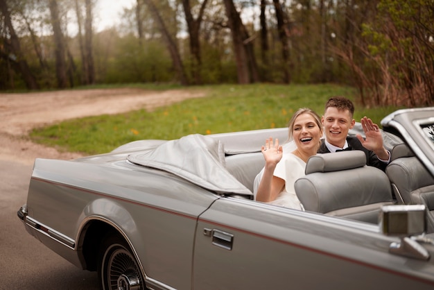 Couple juste marié avec leur voiture