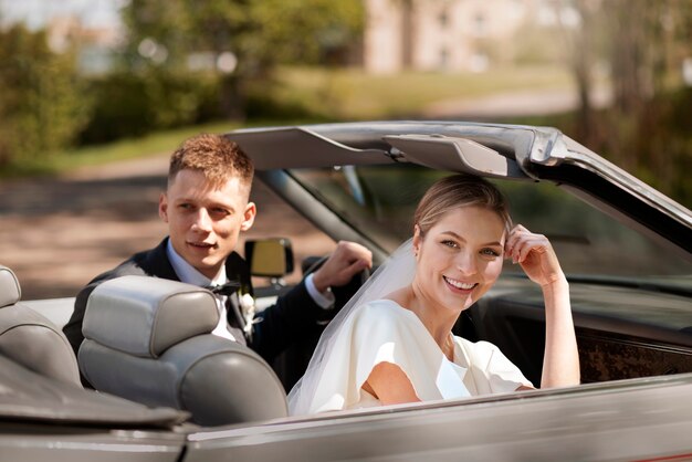 Couple juste marié avec leur voiture