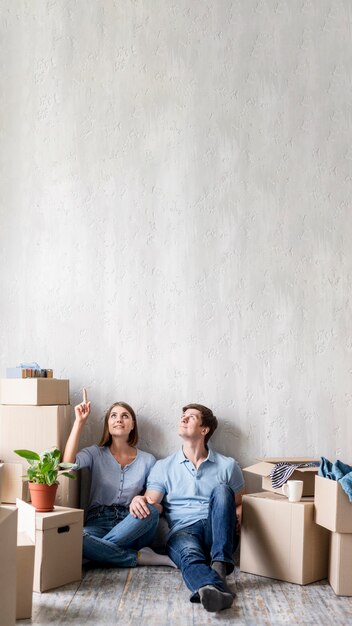 Couple à la maison d'emballage pour sortir et pointer vers le haut