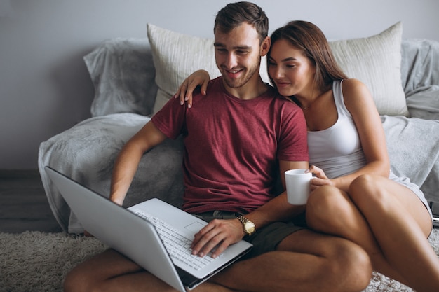 Couple à la maison ensemble assis sur le sol avec un ordinateur