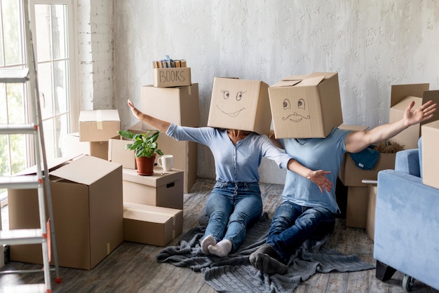 Couple à la maison le jour du déménagement avec des boîtes au-dessus des têtes