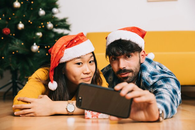 Couple à la maison prenant selfie à noël