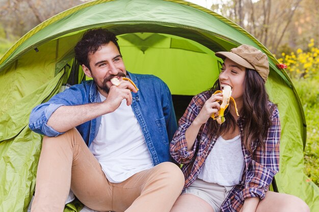 Couple mangeant des bananes près de la tente