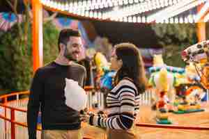 Photo gratuite couple mangeant une barbe à papa dans un parc à thème