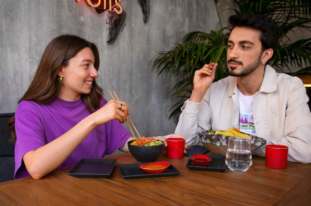 Photo gratuite couple mangeant un bol de plat de saumon au restaurant