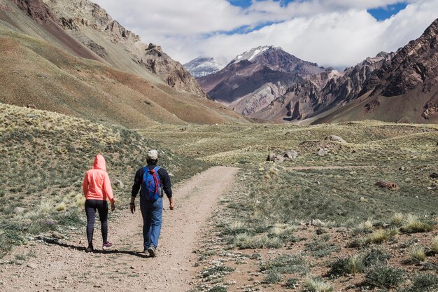 Couple marchant sur la piste de terre près de la chaîne de montagnes