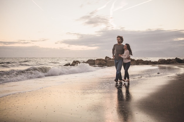 Couple marchant sur la plage au coucher du soleil