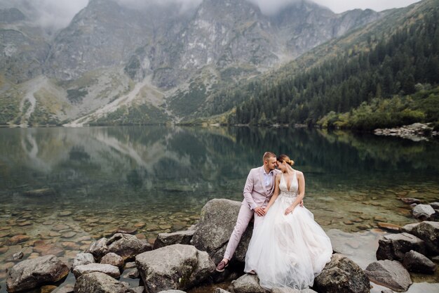 Couple de mariage romantique amoureux debout du lac Sea Eye en Pologne. Montagnes des Tatras.