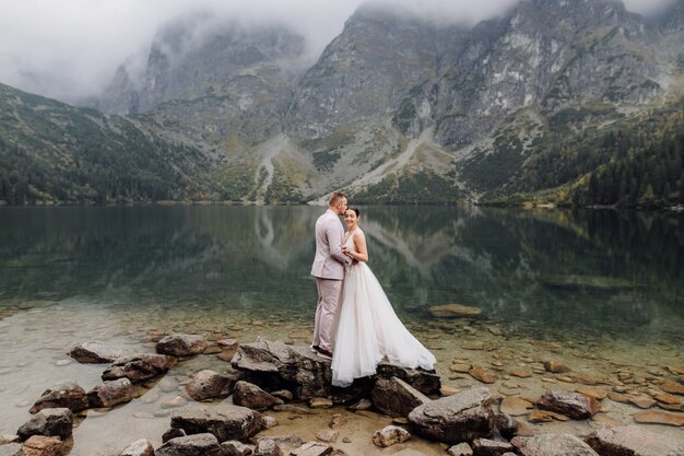 Couple de mariage romantique amoureux debout du lac Sea Eye en Pologne. Montagnes des Tatras.