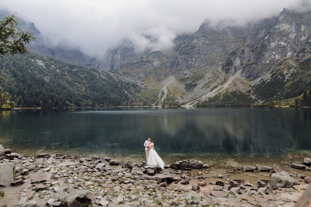 Photo gratuite couple de mariage romantique amoureux debout du lac sea eye en pologne. montagnes des tatras.