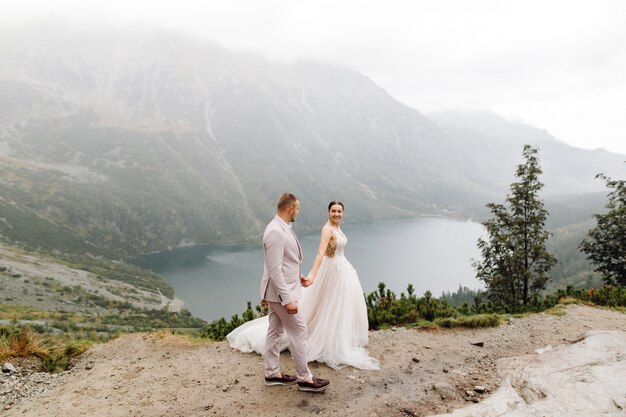 Couple de mariage romantique amoureux debout du lac Sea Eye en Pologne. Montagnes des Tatras.