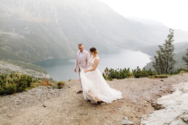 Couple de mariage romantique amoureux debout du lac Sea Eye en Pologne. Montagnes des Tatras.