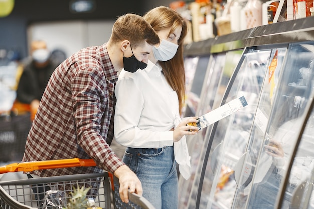 Couple en masque de protection médicale dans un supermarché.