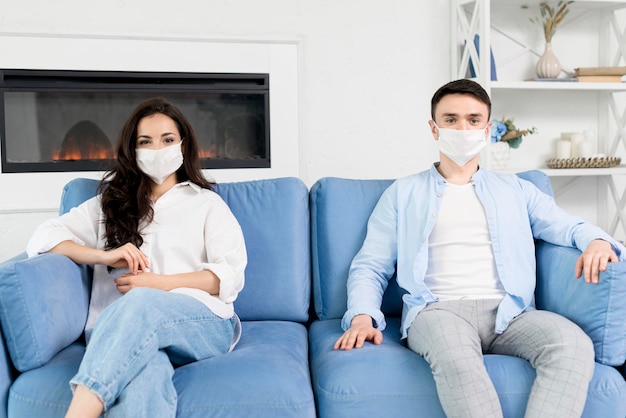 Photo gratuite couple avec masques à la maison sur le canapé