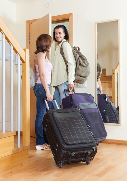 Couple merveilleux avec leurs bagages quittant la maison