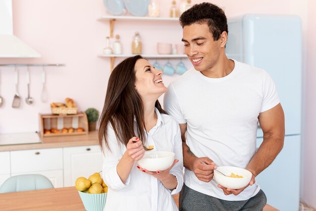 Couple moyen debout debout et en train de manger