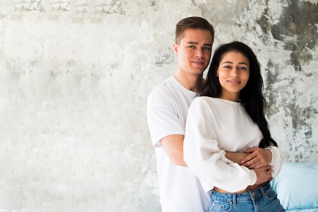 Photo gratuite couple multiracial étreignant et regardant la caméra