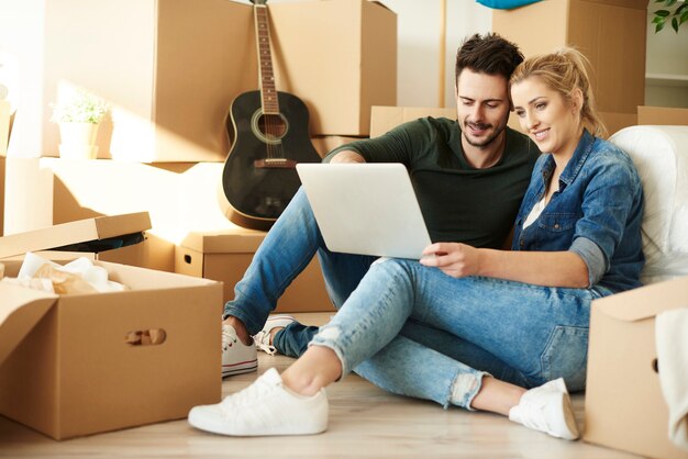 Couple avec ordinateur portable autour de boîtes en carton