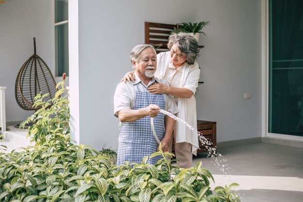 Couple de personnes âgées arroser une fleur dans le jardin