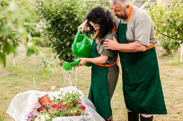 Couple de personnes âgées arroser des fleurs