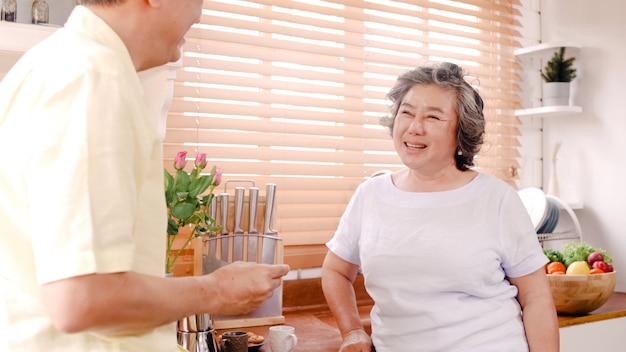 Couple de personnes âgées asiatique prenant son petit déjeuner dans la cuisine à la maison. Couple de chinois doux donnant des biscuits à sa femme à la maison.