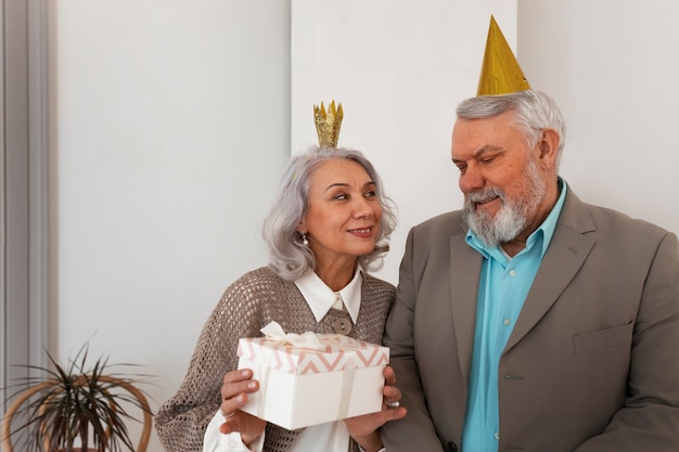 Photo gratuite couple de personnes âgées à coup moyen célébrant avec un cadeau