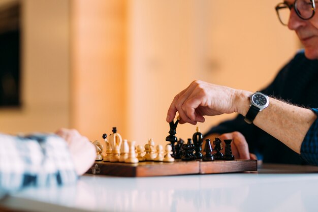 Couple de personnes âgées dans la maison de retraite jouant aux échecs