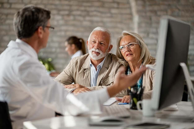 Photo gratuite couple de personnes âgées discutant avec un médecin de leurs dossiers médicaux tout en ayant des consultations à la clinique