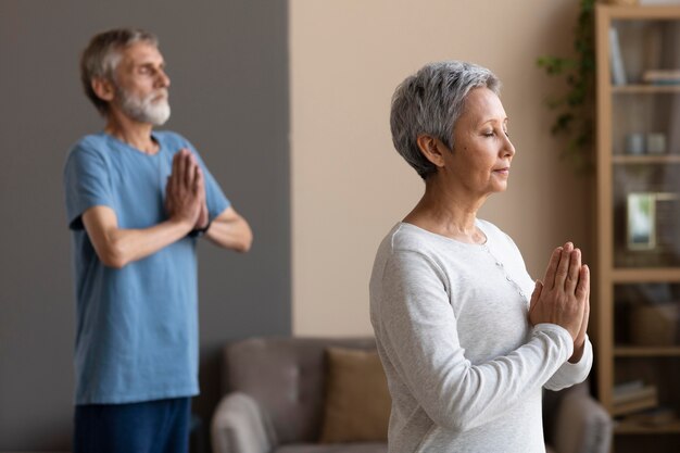 Couple de personnes âgées exerçant ensemble à la maison