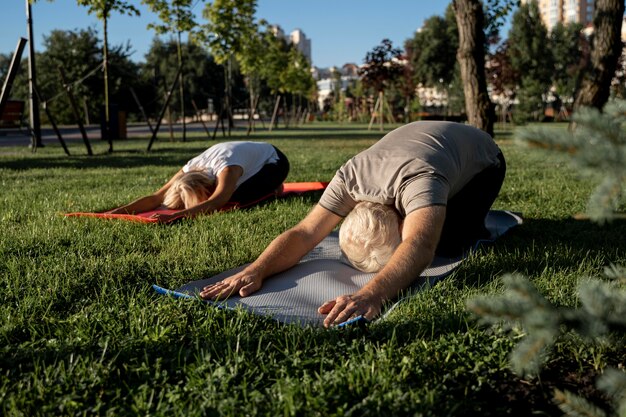 Couple de personnes âgées faisant du yoga à l'extérieur