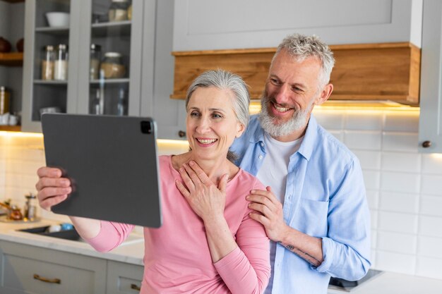 Couple de personnes âgées heureux coup moyen avec tablette