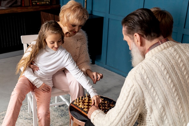 Photo gratuite couple de personnes âgées jouant aux échecs avec leurs petits-enfants