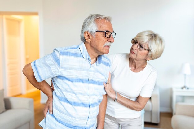 Couple de personnes âgées à la maisonUn homme âgé a mal au dos et sa femme adorable le soutient
