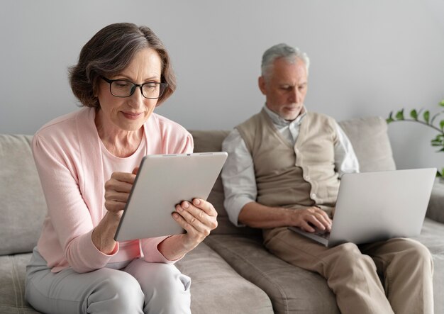 Couple de personnes âgées à plan moyen avec des appareils